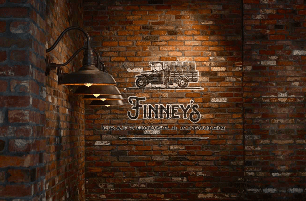 photo of a thin brick veneer wall inside the brewery with the word Finney's painted on it.
