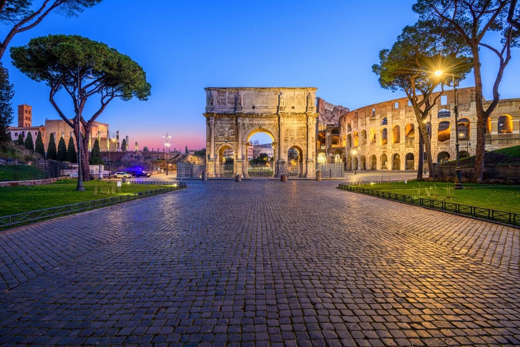 A picture of a cobblestone road leading to the Colosseum in Rome at dusk.