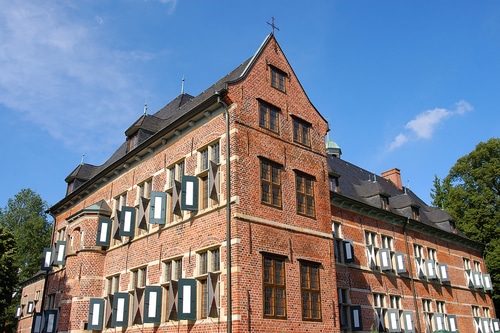 photo of Germany's Reinbek Castle.  Close up of the large red brick castle, with many rectangular windows, and a cross atop the highest point of the roof.