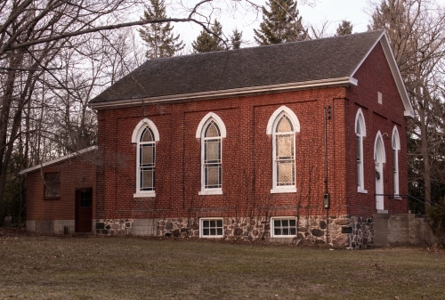 photo of an old red brick church, with white window frames, arched at the tops.