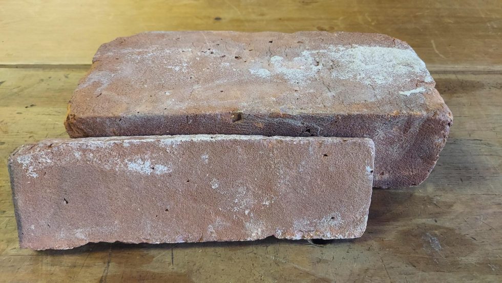 A sample of New England mill blend reclaimed face brick, with a thin veneer piece in front of it.