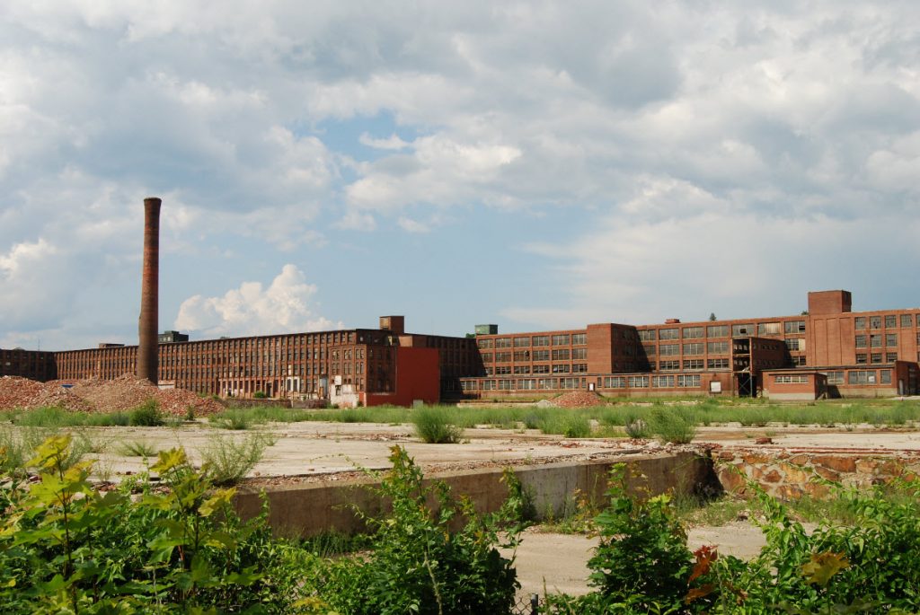 The Draper Mill, sitting abandoned, with weeds growing in the foreground.