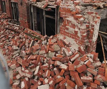 A pile of bricks from the Draper Mill in front of a partially demolished building.