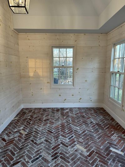 Reclaimed brick wall tile in a herringbone design in a newly constructed, unfurnished room.