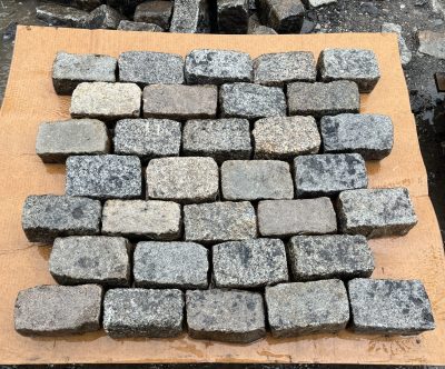 The top halves of granite cobbles that have been split in two, laid out on a piece of cardboard, in the rain.