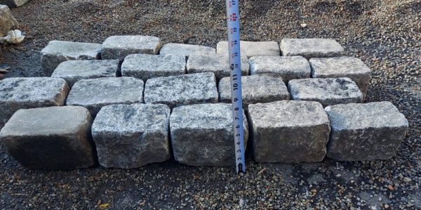 Granite cobbles staged to stand with their longest side horizontal, and a tape measure placed in front to display their height.