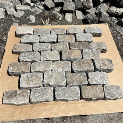 The bottom halves of granite cobbles that have been split in two, laid out on a piece of cardboard.