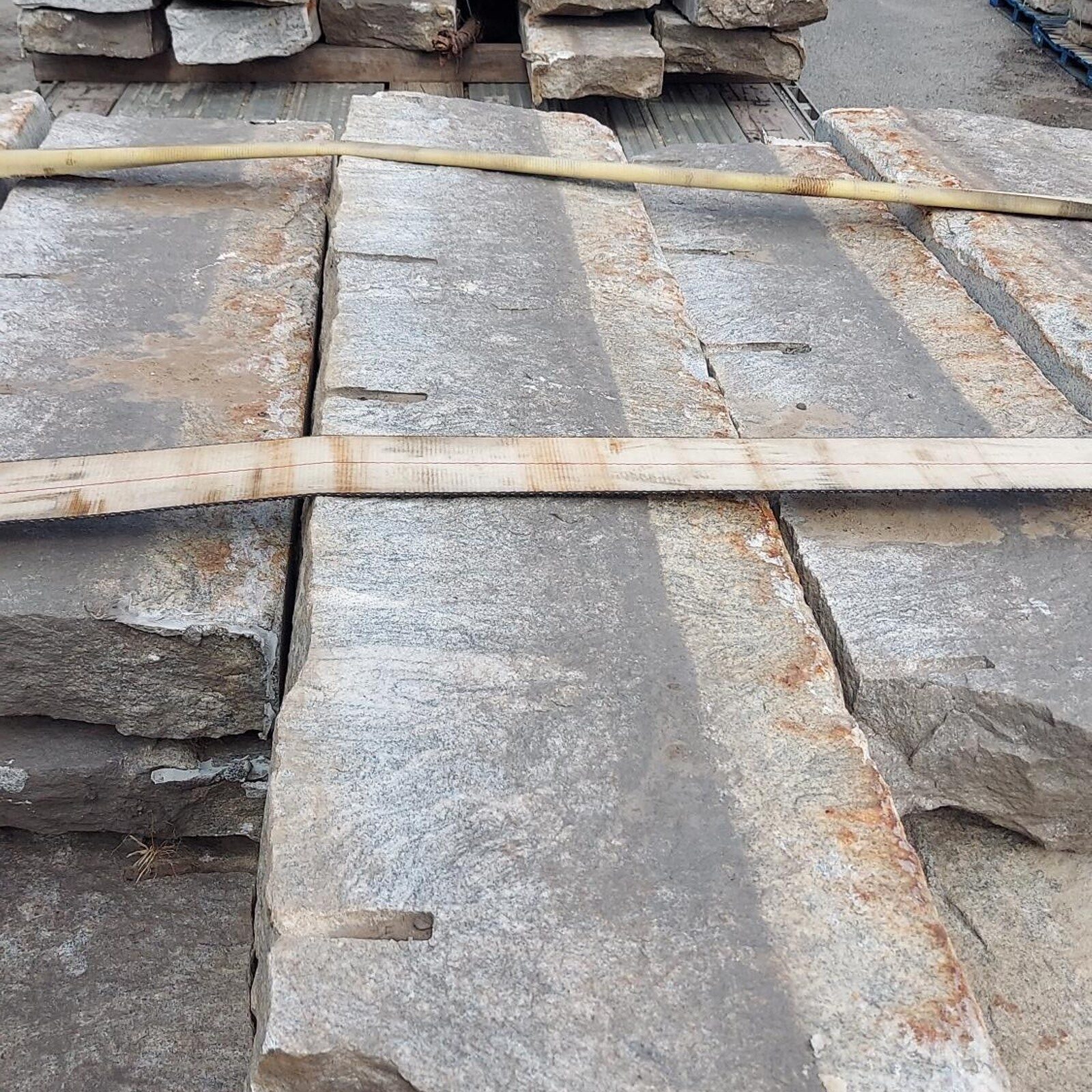 reclaimed paving grade curb pieces stacked on pallets.
