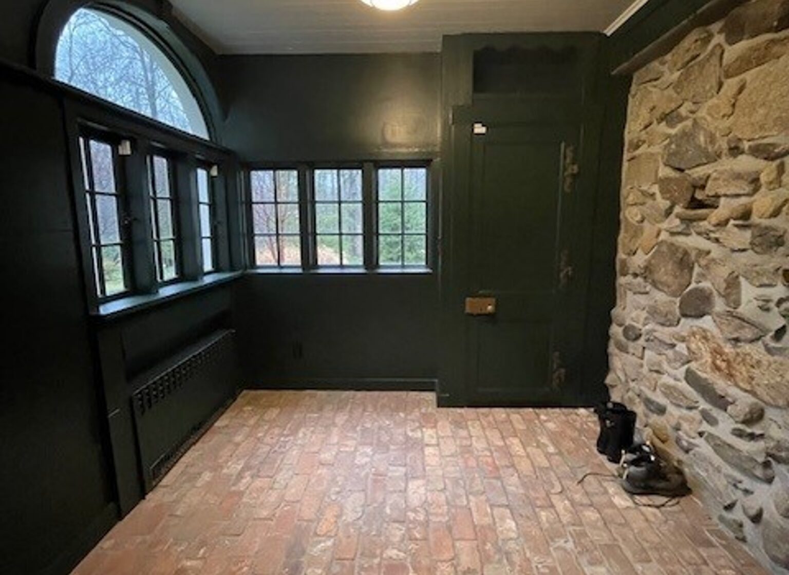 Mudroom with reclaimed brick tile floors and forest green walls.