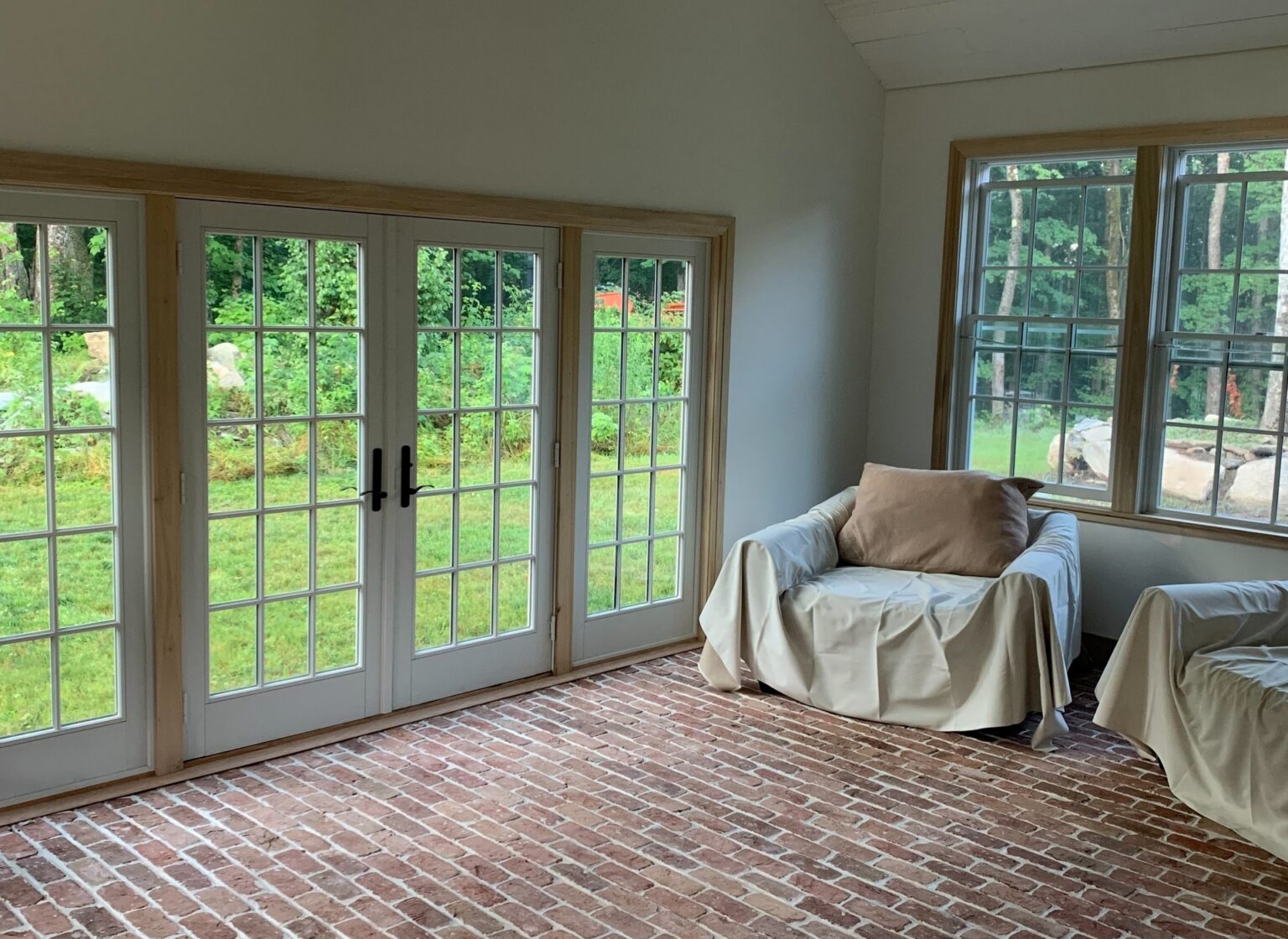 Sunroom with a reclaimed brick floor and large French doors.