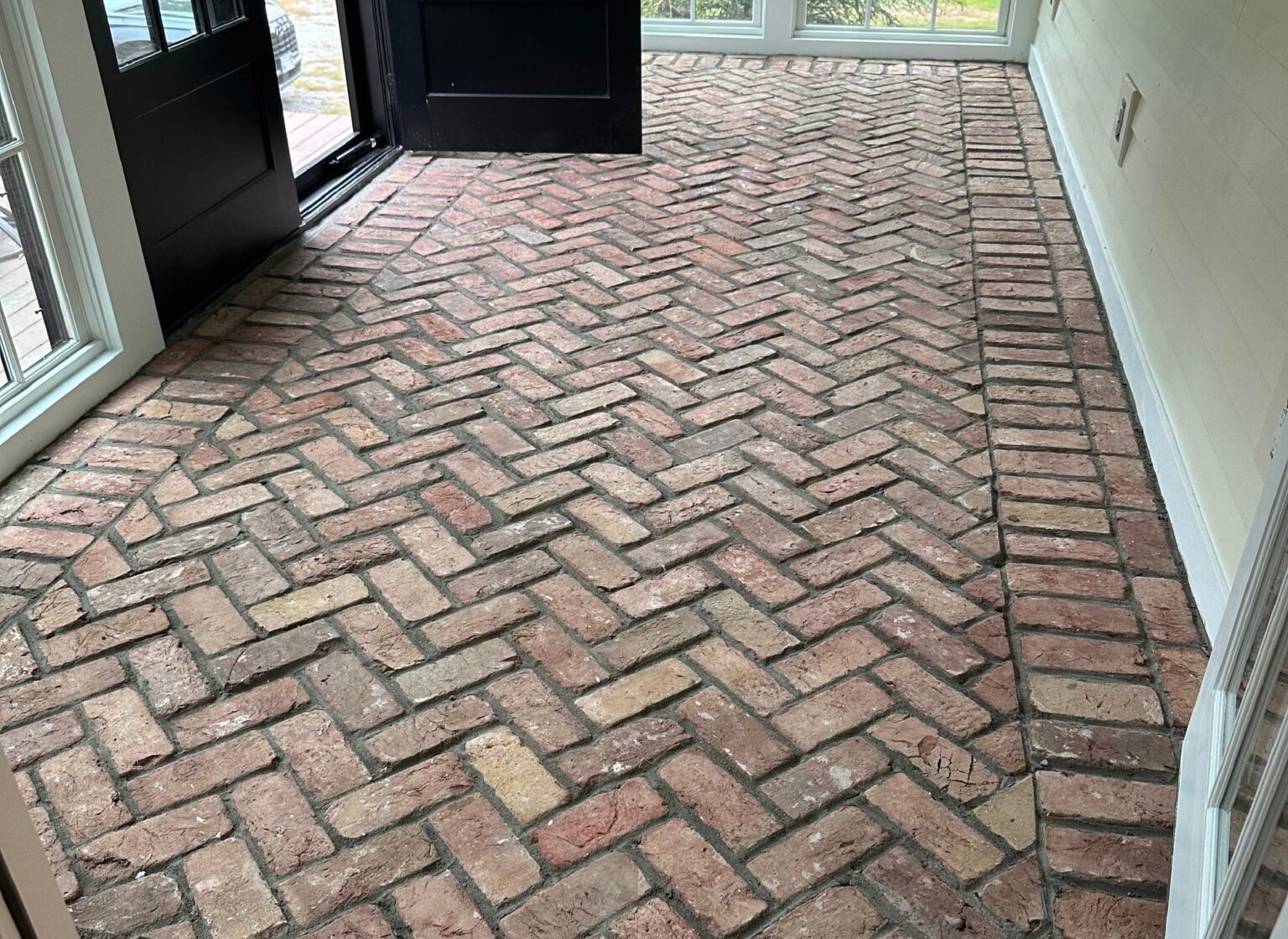 Mudroom with a reclaimed herringbone brick floor.