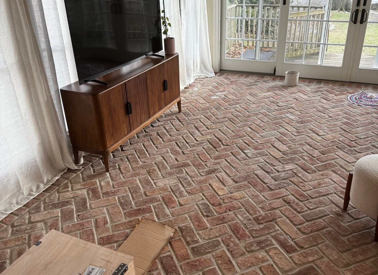 Living room with antique brick floor, featuring a TV stand and TV.