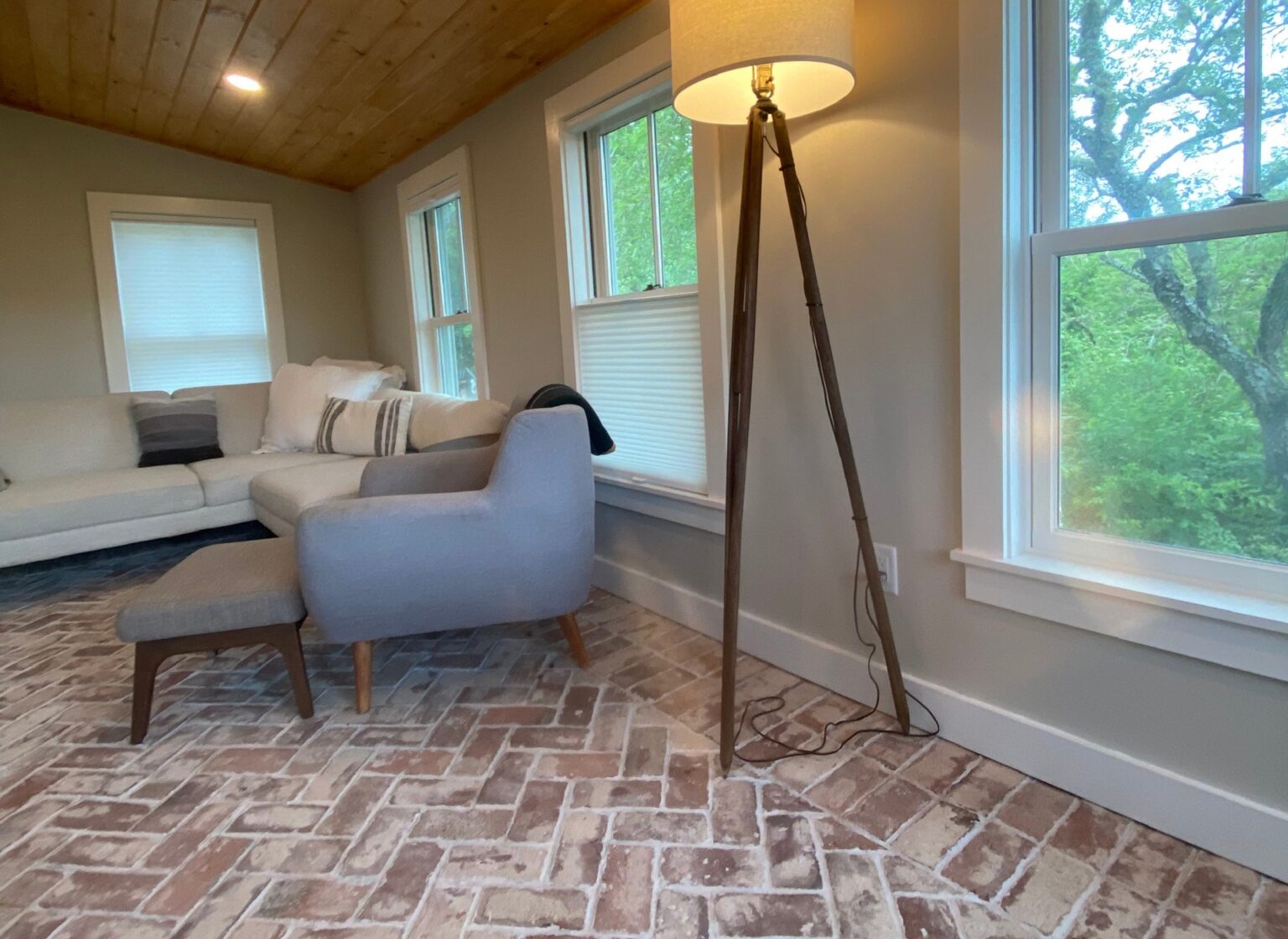 Living room with a reclaimed brick floor featuring a couch, chair, and tall lamp.
